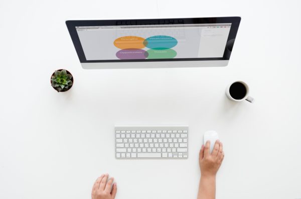 person at a computer with a coffee cup